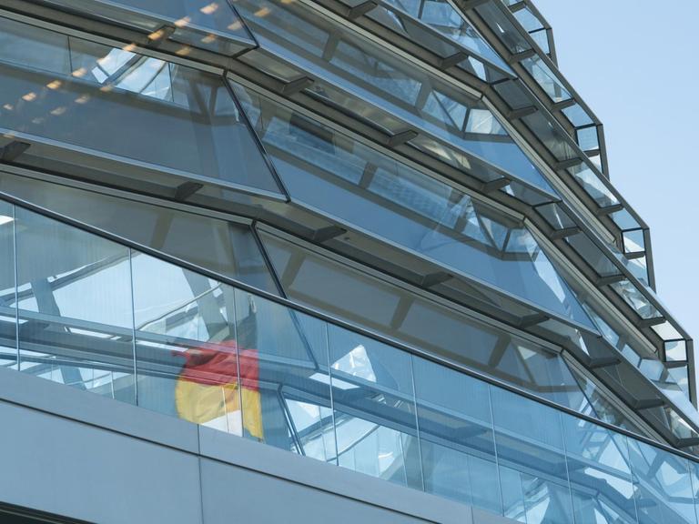 Die deutsche Fahne spiegelt sich in der Kuppel des Bundestages.