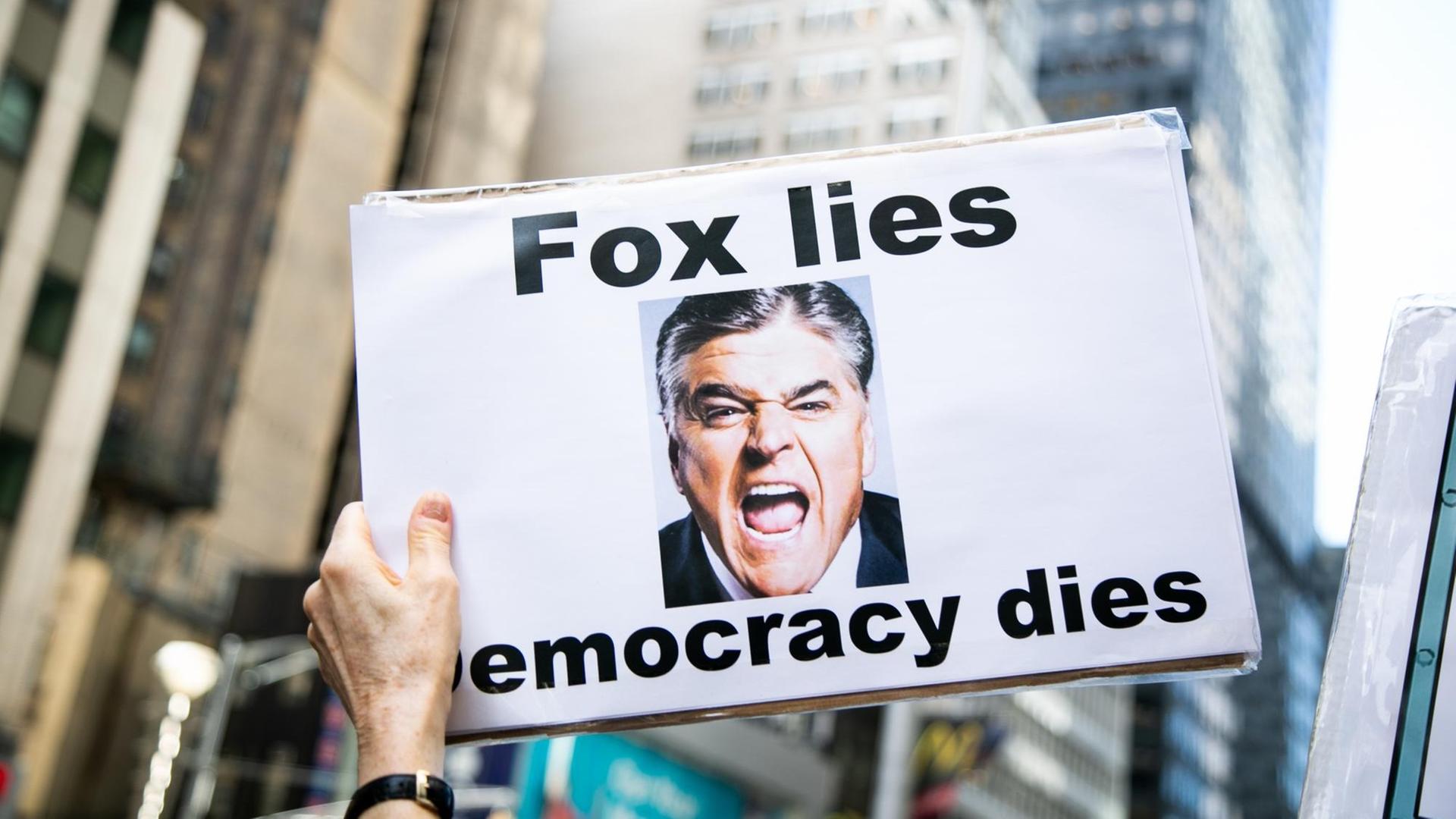 Eine Demonstrantin hält ein Schild mit der Aufrschrift "Fox lies, democracy dies". Eine Demonstrantin hält ein Schild mit der Aufrschrift "Fox lies, democracy dies".