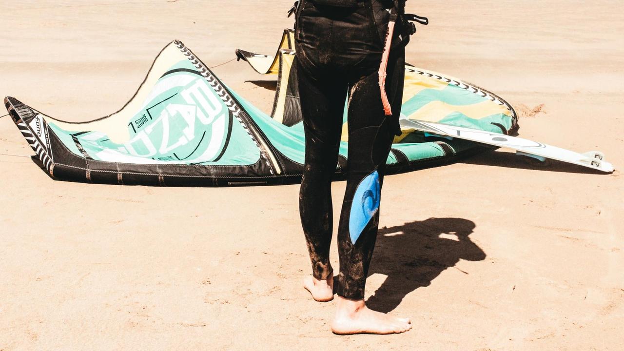 Ein Mann macht sich am Strand bereit zum Kitesurfen. Ein Mann macht sich am Strand bereit zum Kitesurfen.
