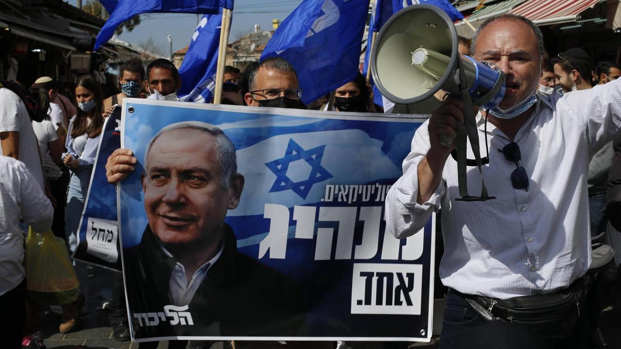 Anhänger der Likud Partei im Wahlkampf auf der Strasse in Jerusalem auf palästinensischem Gebiet. Sie halten einen Banner mit Premierminister Benjamin Netanyahu in den Händen. 19. März 2021. Anhänger der Likud Partei im Wahlkampf auf der Strasse in Jerusalem auf palästinensischem Gebiet. Sie halten einen Banner mit Premierminister Benjamin Netanyahu in den Händen. 19. März 2021.