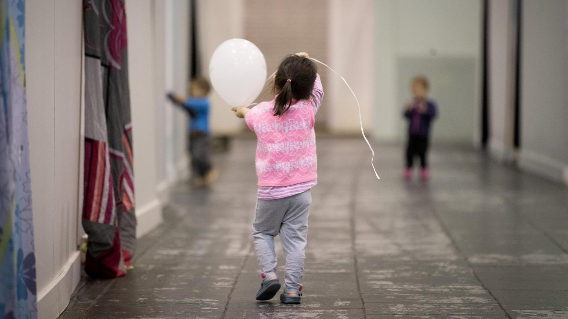 Ein Flüchtlingskind läuft in Berlin durch den Hangar 2 der Flüchtlings-Notunterkunft auf dem ehemaligen Flughafen Tempelhof. Ein Flüchtlingskind läuft in Berlin durch den Hangar 2 der Flüchtlings-Notunterkunft auf dem ehemaligen Flughafen Tempelhof.
