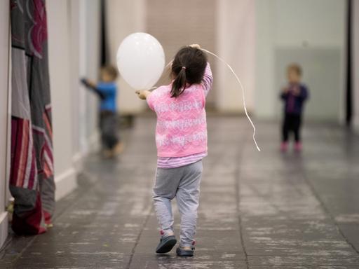 Ein Flüchtlingskind läuft in Berlin durch den Hangar 2 der Flüchtlings-Notunterkunft auf dem ehemaligen Flughafen Tempelhof. Ein Flüchtlingskind läuft in Berlin durch den Hangar 2 der Flüchtlings-Notunterkunft auf dem ehemaligen Flughafen Tempelhof.
