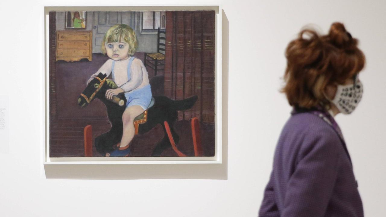 Blick in die Ausstellung: Eine Frau steht neben einem Gemälde von Alice Neel. Darauf zu sehen ist ein Junge auf einem Schaukelpferd. Blick in die Ausstellung: Eine Frau steht neben einem Gemälde von Alice Neel. Darauf zu sehen ist ein Junge auf einem Schaukelpferd.