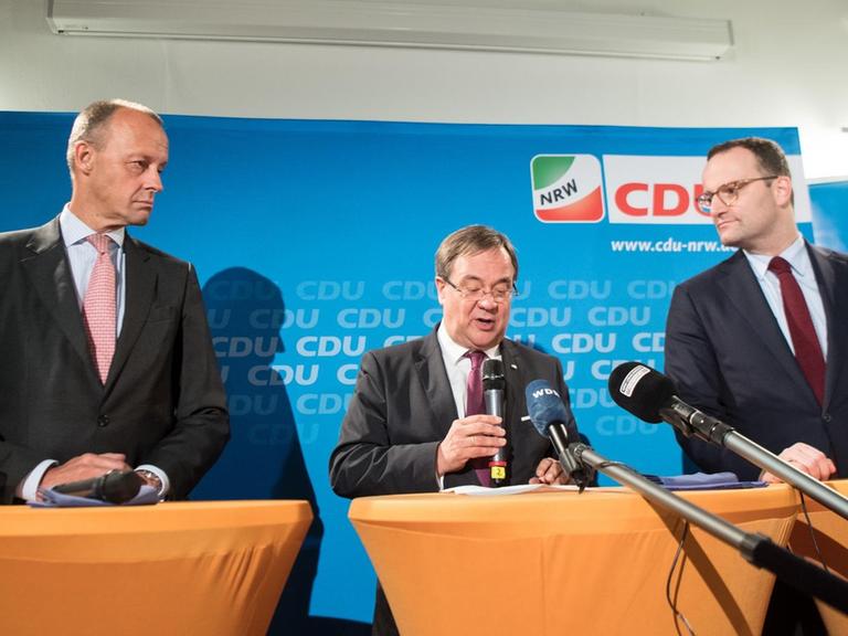 Friedrich Merz (l-r), Armin Laschet, Ministerpräsident von Nordrhein-Westfalen und Jens Spahn, Bundes-Gesundheitsminister sitzen bei einer Pressekonferenz gemeinsam auf dem Podium.