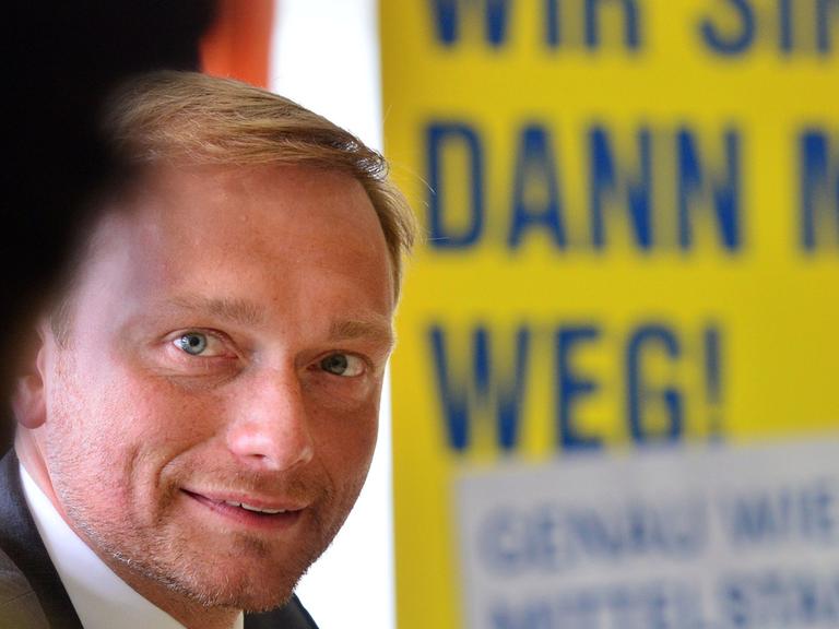 Der FDP-Bundesvorsitzende, Christian Lindner, sitzt am 06.08.2014 in Erfurt (Thüringen) bei einer Wahlkampfveranstaltung vor einem Wahlplakat der Thüringer FDP auf dem steht: "Wir sind dann mal weg. Genauso wie der Mittelstand"