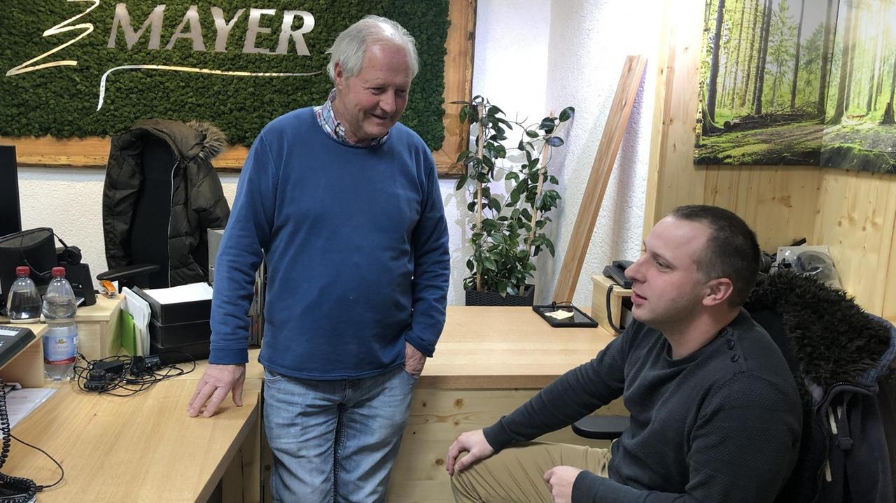 Seniorchef Mayer und der Vertriebsleiter Raphael Klimm. Ein älterer Mann spricht mit einem jüngeren Mann in einem Büro. Seniorchef Mayer und der Vertriebsleiter Raphael Klimm. Ein älterer Mann spricht mit einem jüngeren Mann in einem Büro.