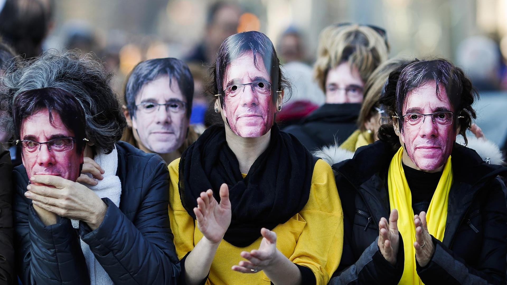 Demonstranten in Barcelona tragen Masken mit der Abbildung des separatistischen Politikers Puigdemont. Demonstranten in Barcelona tragen Masken mit der Abbildung des separatistischen Politikers Puigdemont.