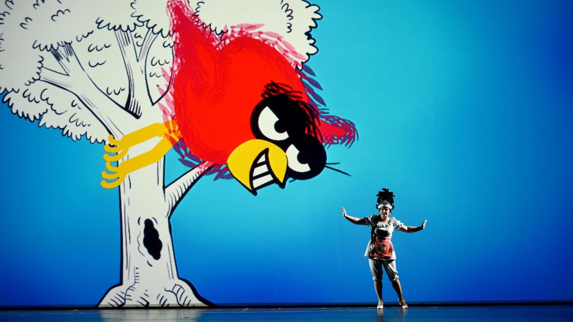 Probe zur Rossini-Oper "Die Reise nach Reims" im Opernhaus Kiel (2017): eine Frau steht auf der Bühne, im Hintergrund ein Baum mit einem großen Vogel.