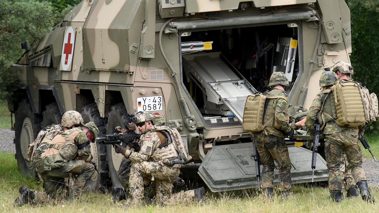 Soldaten bergen während einer Übung einen Kameraden, der einen verletzten Soldaten simuliert, und transportieren ihn in ein gepanzertes Transportfahrzeug. Soldaten bergen während einer Übung einen Kameraden, der einen verletzten Soldaten simuliert, und transportieren ihn in ein gepanzertes Transportfahrzeug.