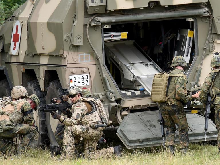 Soldaten bergen während einer Übung einen Kameraden, der einen verletzten Soldaten simuliert, und transportieren ihn in ein gepanzertes Transportfahrzeug. Soldaten bergen während einer Übung einen Kameraden, der einen verletzten Soldaten simuliert, und transportieren ihn in ein gepanzertes Transportfahrzeug.