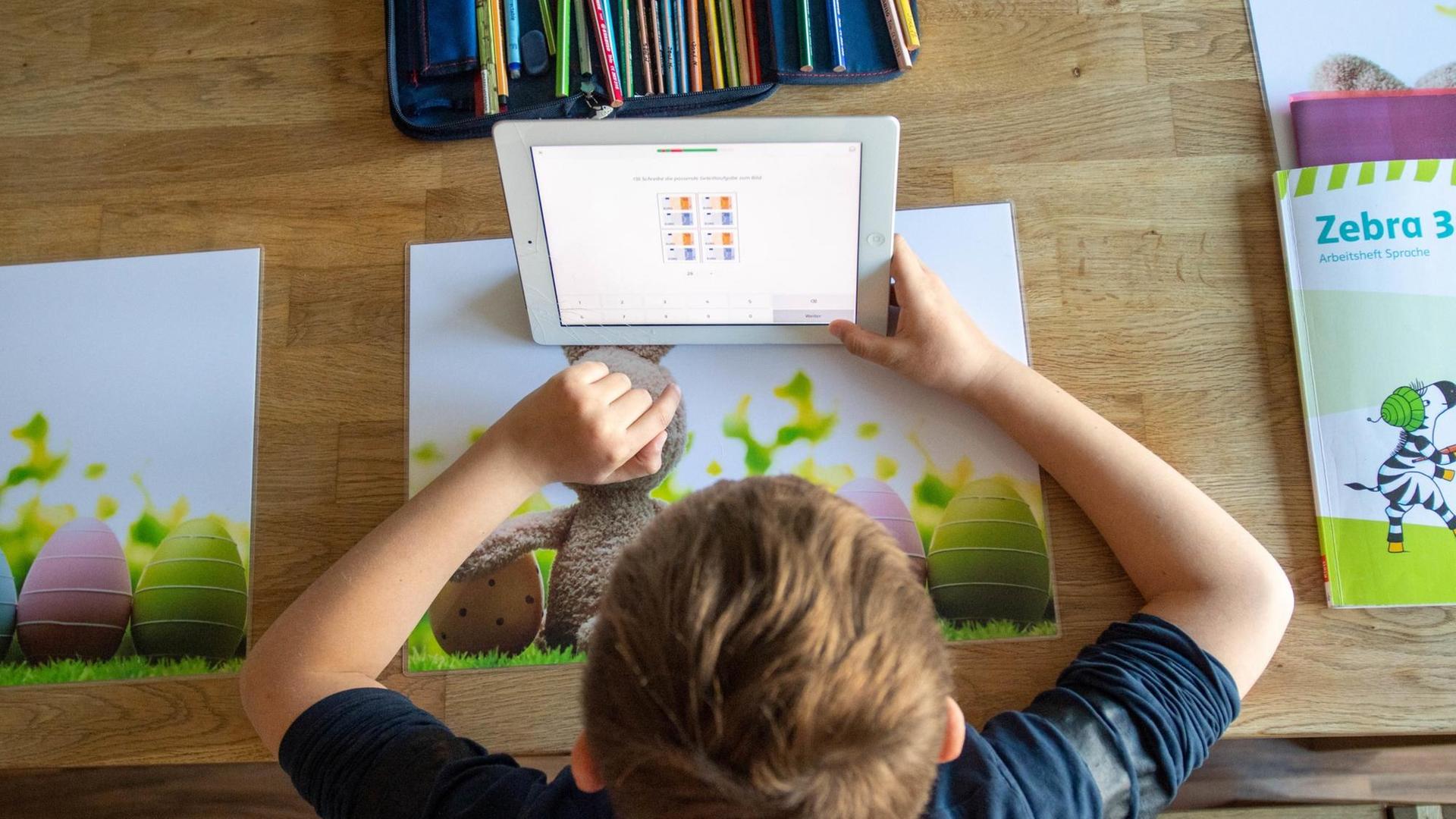 Ein Junge löst zu Hause seine Schulaufgaben am Ipad. Ein Junge löst zu Hause seine Schulaufgaben am Ipad.