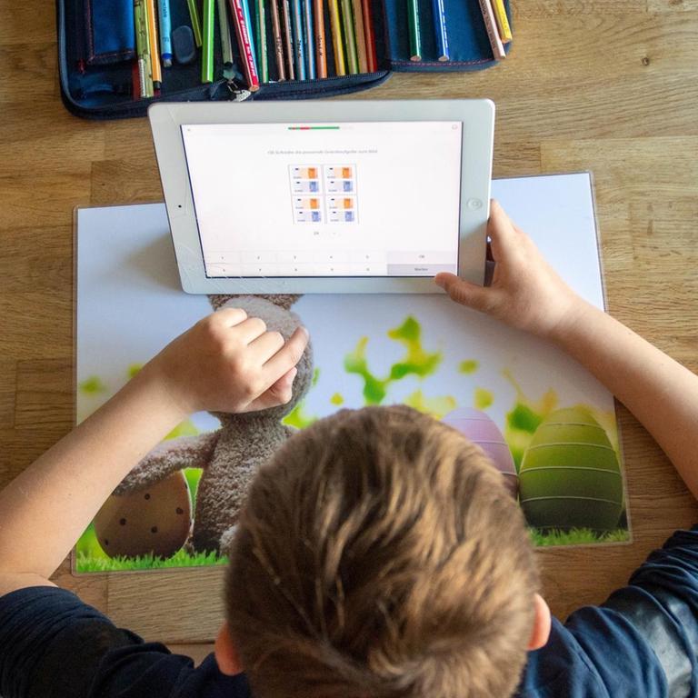 Ein Junge löst zu Hause seine Schulaufgaben am Ipad.