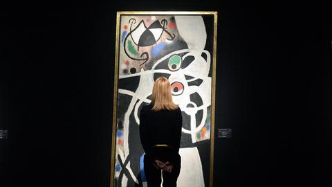 Eine Mitarbeiterin des Auktionshauses Christie's in London betrachtet am 30.1.2014 das Bild 'Femmes et oiseaux' des spanischen Malers Joan Miro.