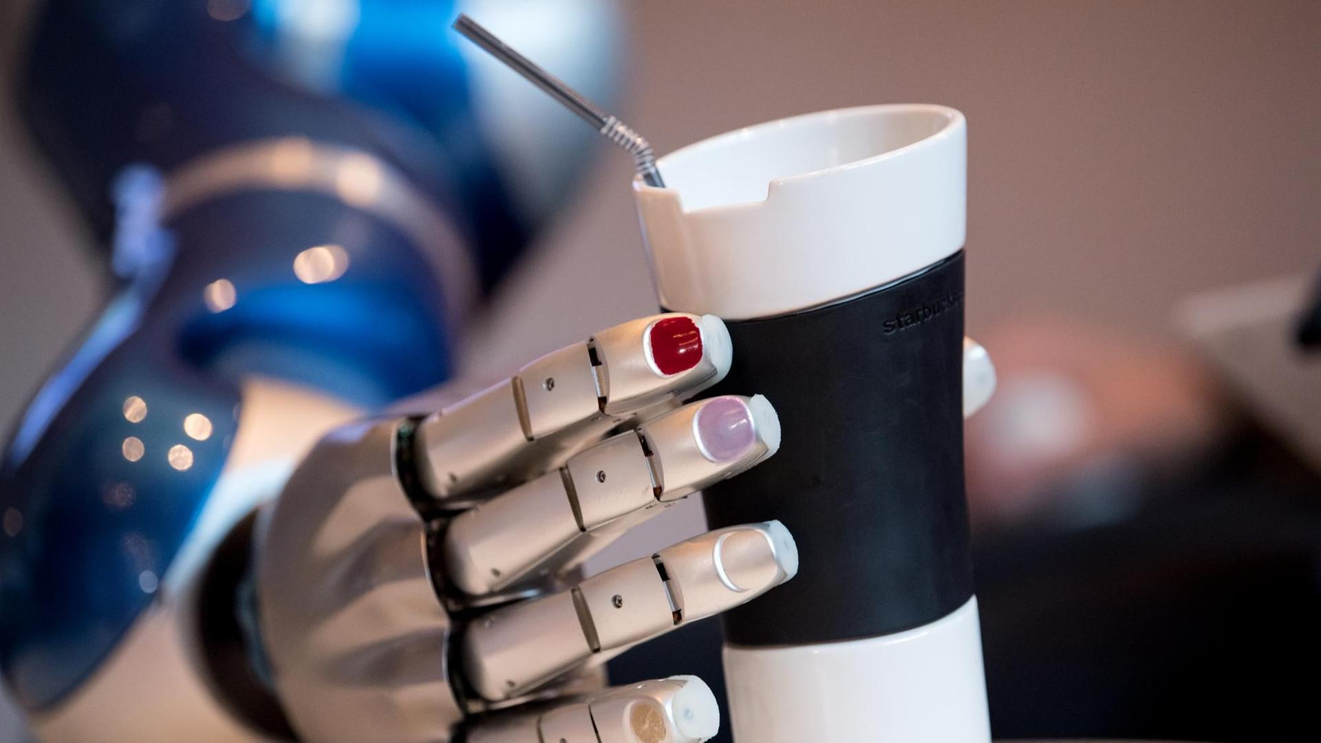 Eine Mitarbeiterin vom Deutschen Zentrum für Luft und Raumfahrt (DLR) stellt bei einer Pressekonferenz den Assistenzroboter EDAN (EMG-controlled daily assistant) vor, der nach einem Getränk greift. Eine Mitarbeiterin vom Deutschen Zentrum für Luft und Raumfahrt (DLR) stellt bei einer Pressekonferenz den Assistenzroboter EDAN (EMG-controlled daily assistant) vor, der nach einem Getränk greift.
