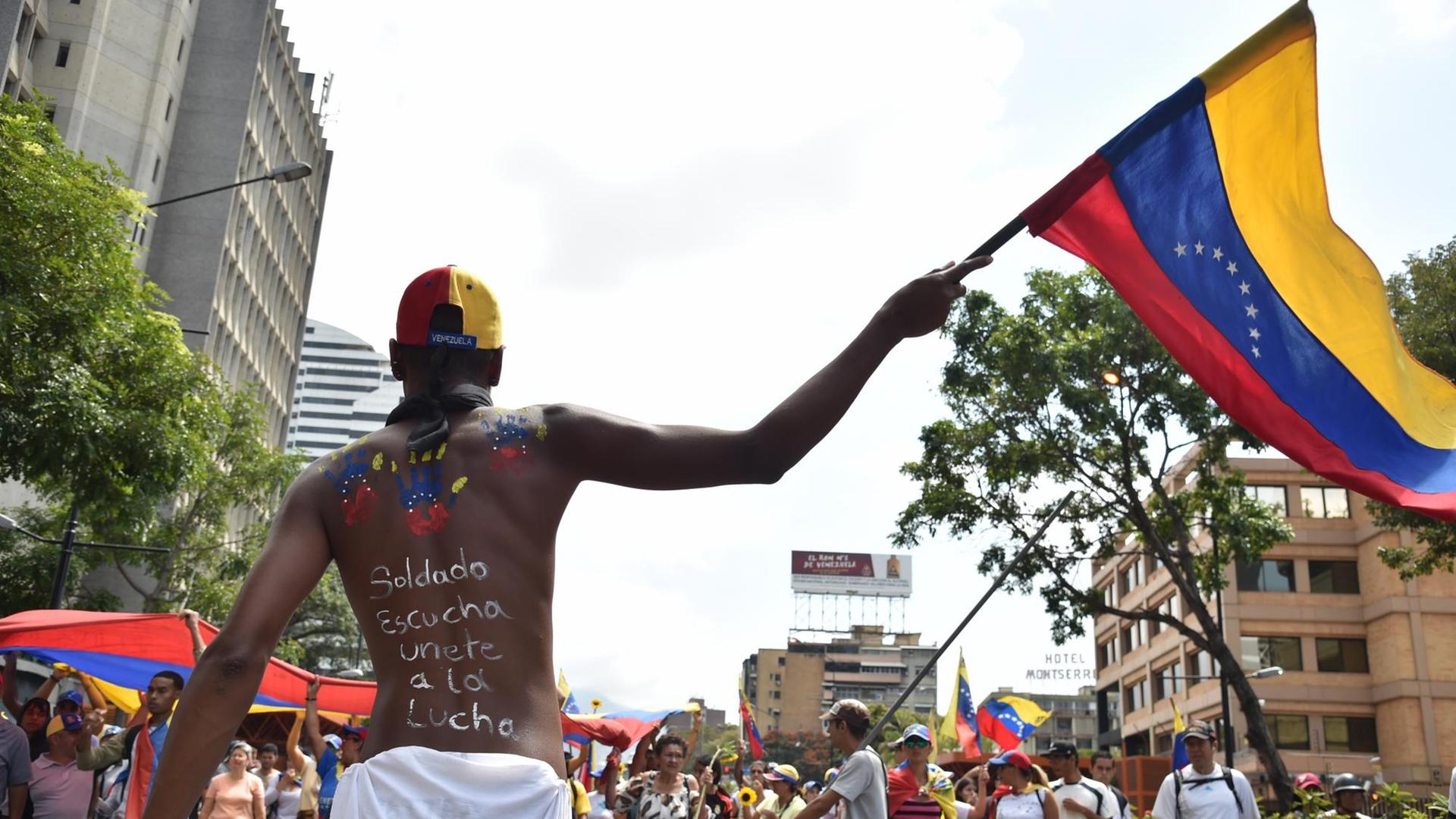 Ein Anhänger des venezolanischen Oppositionsführers und selbsternannten Übergangspräsidenten Juan Guaido bei Protesten mit einer Nationalflagge in der Hand.