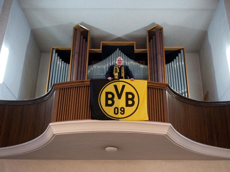 Pfarrer Ansbert Junk steht am Freitag (10.12.2010) in der Dreifaltigkeitskirche in Dortmund auf der Orgelempore, an der eine BVB-Fahne hängt. Dortmund ist ganz oben. Der Siegeskurs der Fußballer von Borussia verleiht der Ruhrgebietsstadt ein völlig neues Selbstvertrauen
