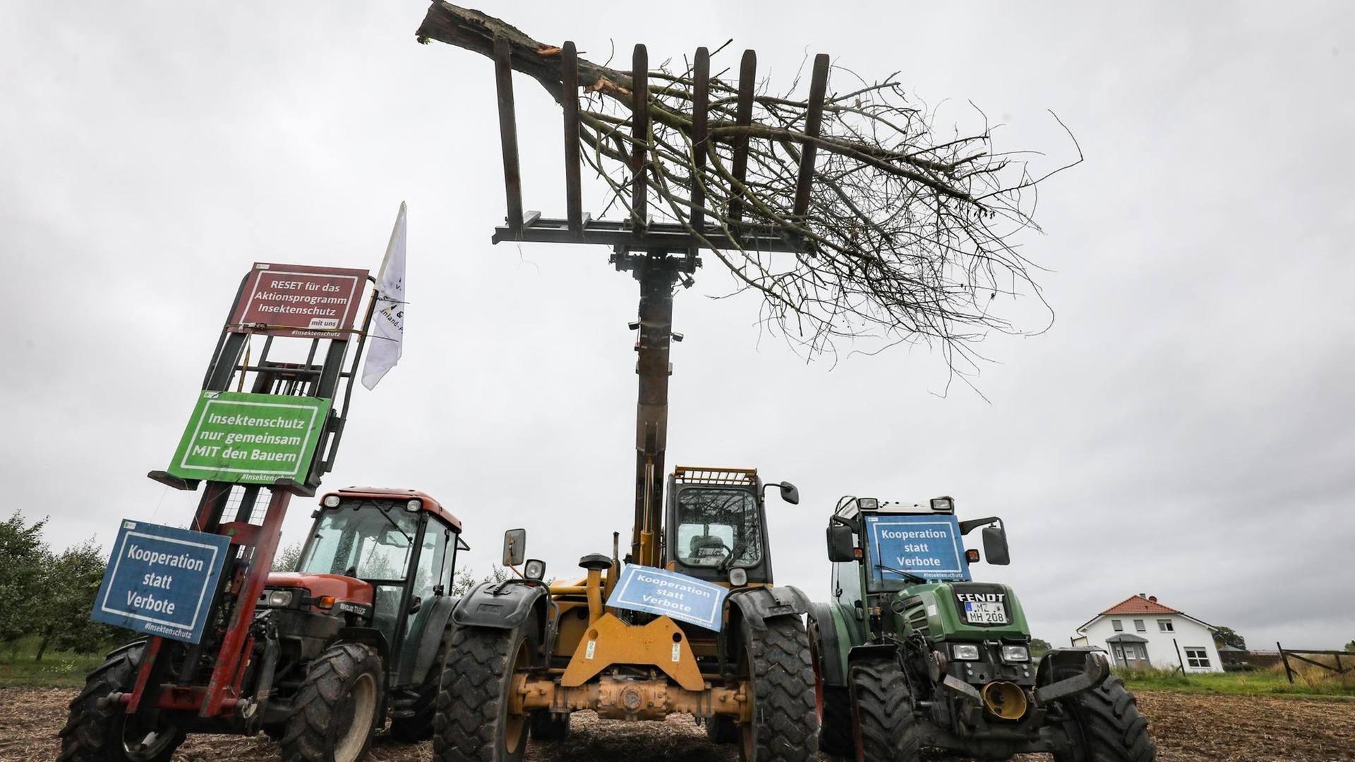 Mit einem toten Obstbaum auf einer Ladeschaufel protestieren Bauern am Rande des Tagungshotels der Agrarministerkonferenz (AMK).