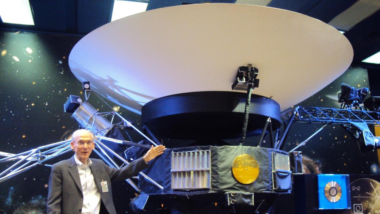 Der Chef des Voyager-Programms, Ed Stone steht neben einem Modell der Raumsonde Voyager.