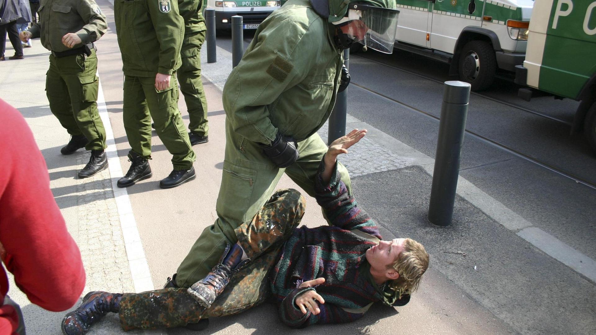 Ein Polizist steht drohend über einem Punk, der am Boden liegt. Ein Polizist steht drohend über einem Punk, der am Boden liegt.