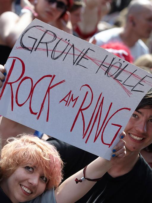 Zuschauer zeigen am 06.06.2014 beim Rockfestival "Rock am Ring" auf dem Nürburgring eine Tafel, mit der sie gegen die Nachfolgeveranstaltung "Grüne Hölle-Rockfestival" protestieren.