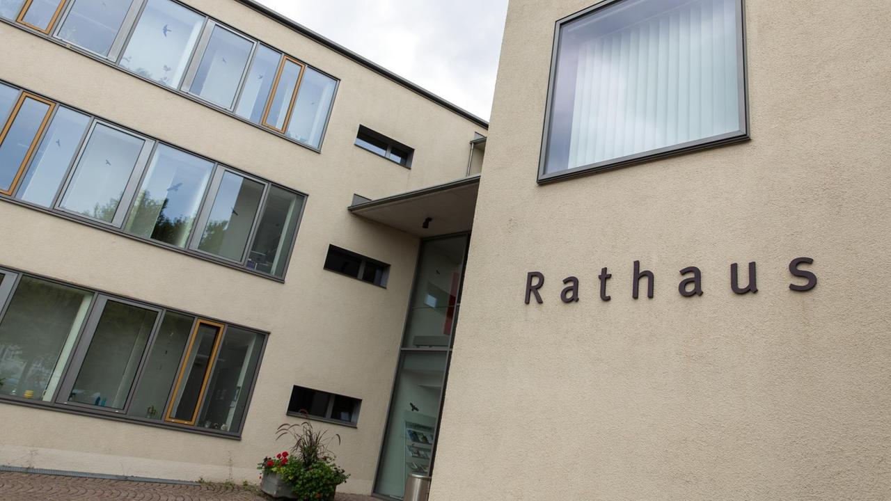 Ein moderner Bau mit mehreren Flügeln und Flachdach, im Vordergrund steht Rathaus an der Wand. Ein moderner Bau mit mehreren Flügeln und Flachdach, im Vordergrund steht Rathaus an der Wand.