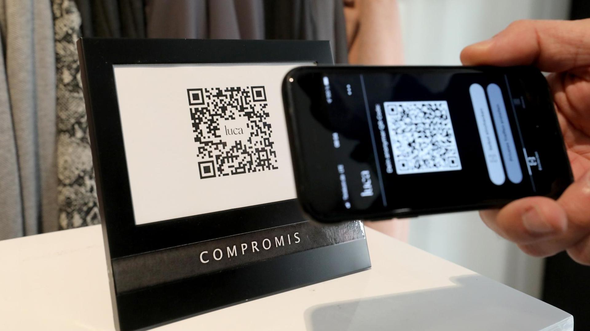 Ein Mann checkt in ein Geschäft ein, indem er den QR-Code des Geschäfts mit seiner Luca-App scannt. Ein Mann checkt in ein Geschäft ein, indem er den QR-Code des Geschäfts mit seiner Luca-App scannt.