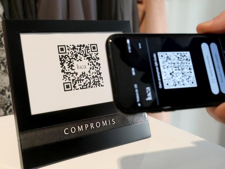 Ein Mann checkt in ein Geschäft ein, indem er den QR-Code des Geschäfts mit seiner Luca-App scannt.