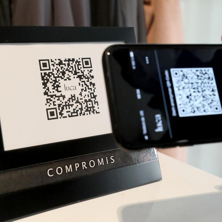 Ein Mann checkt in ein Geschäft ein, indem er den QR-Code des Geschäfts mit seiner Luca-App scannt.