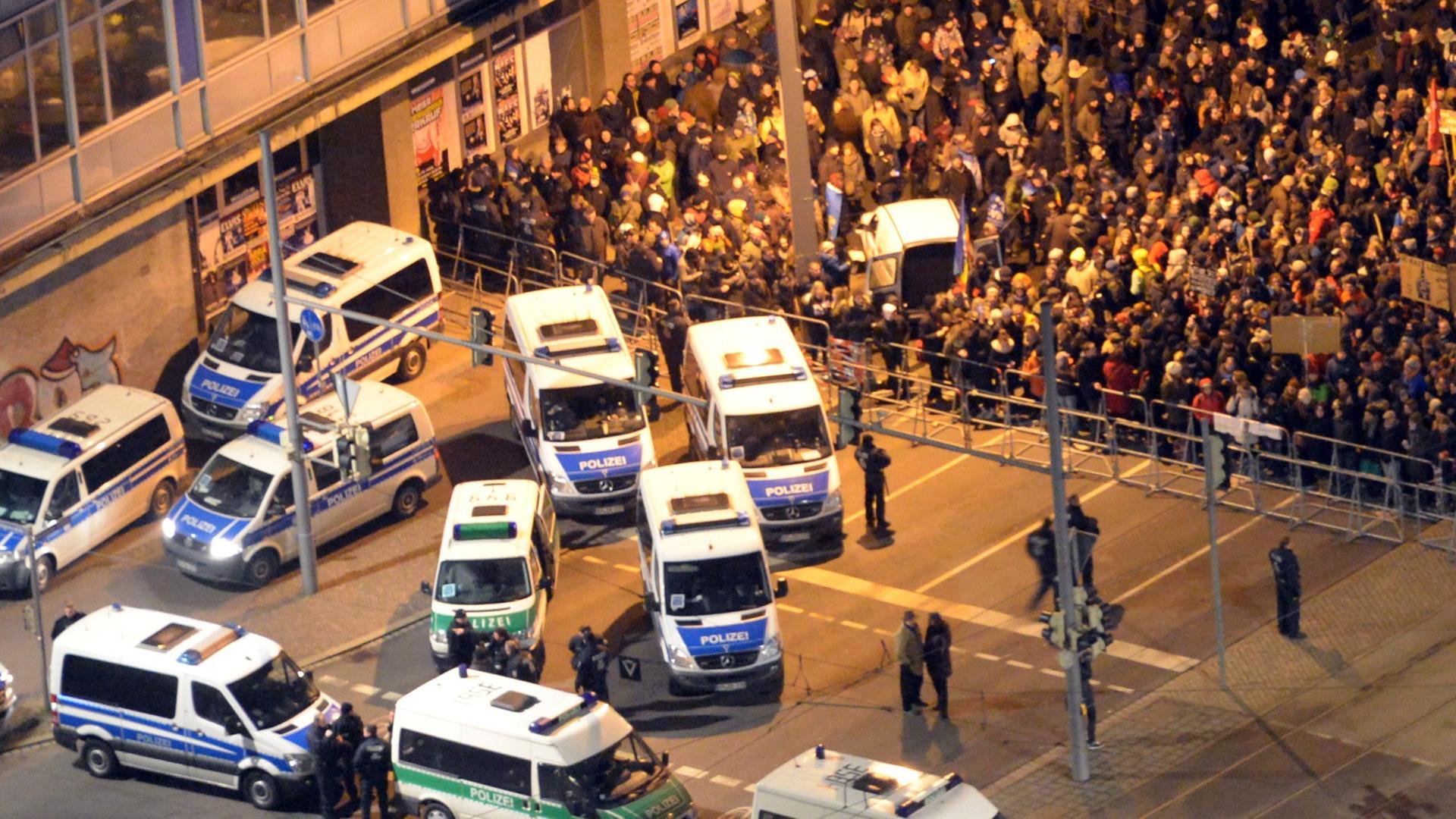 Luftaufnahme der Gegendemo. Demonstranten stehen hinter einer Absperrung, davor ein Dutzend Einsatzfahrzeuge der Polizei. Luftaufnahme der Gegendemo. Demonstranten stehen hinter einer Absperrung, davor ein Dutzend Einsatzfahrzeuge der Polizei.
