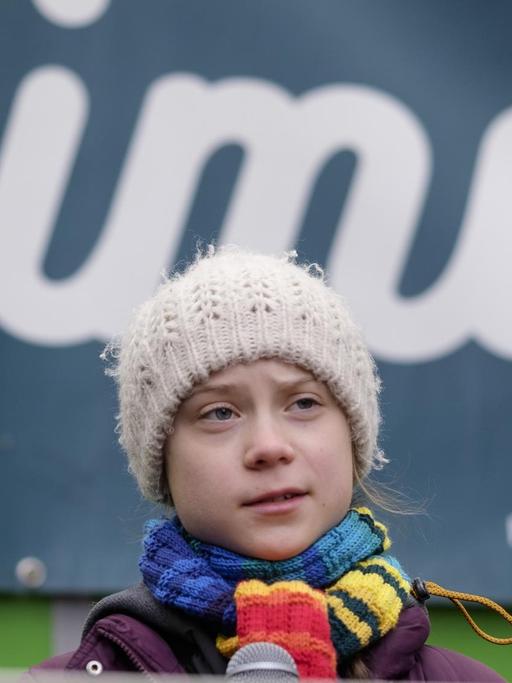 Die Klimaaktivistin Greta Thunberg steht vor einem Banner auf dem „Climate“ steht.