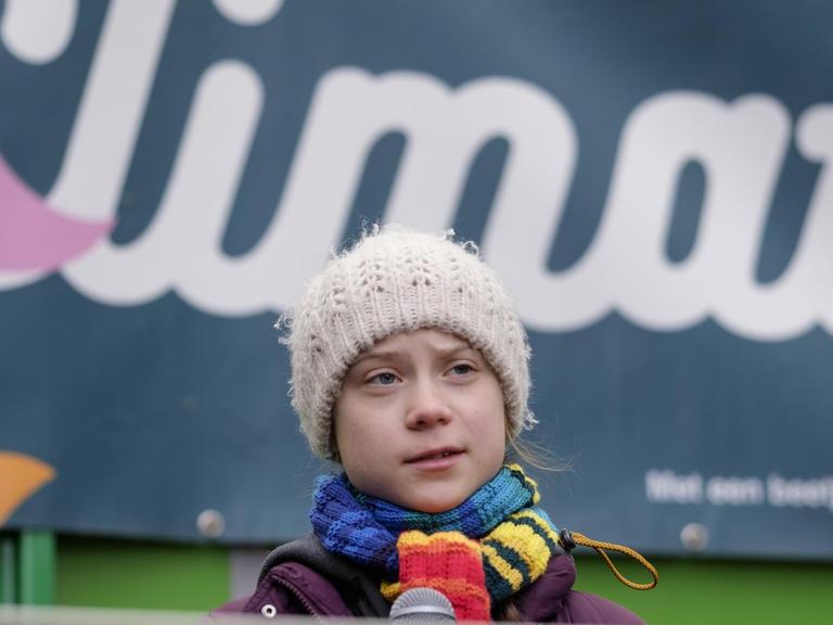 Die Klimaaktivistin Greta Thunberg steht vor einem Banner auf dem „Climate“ steht.