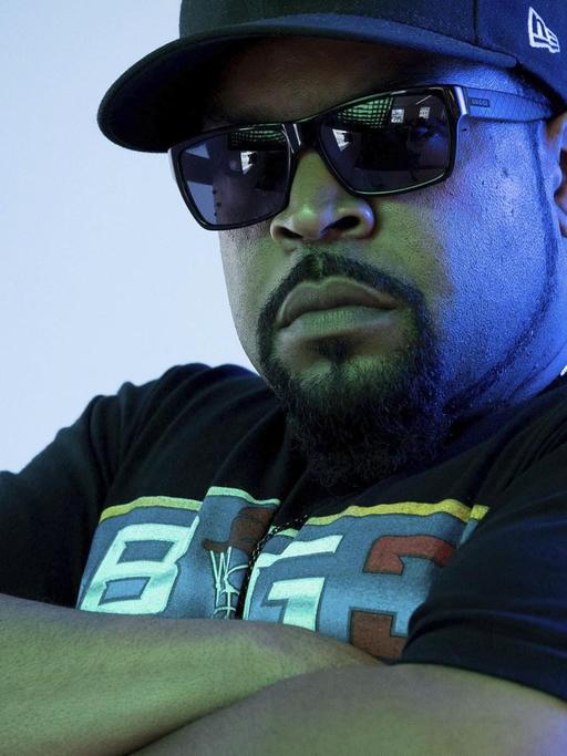 Der Rapper Ice Cube mit Cappy, Sonnenbrille und verschränkten Armen.
