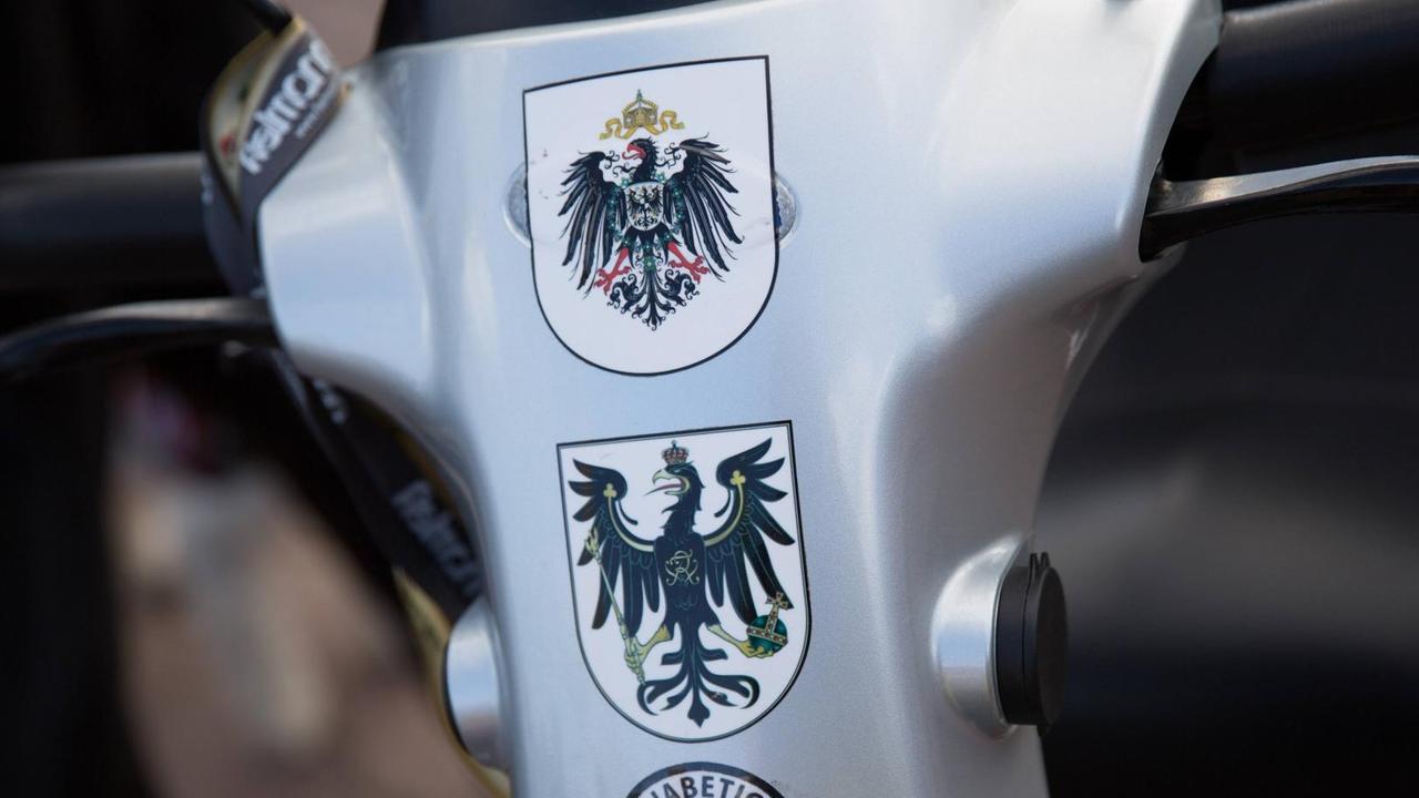 Mehrere Wappen als Statement für eine Monarchie nach Vorbild des Deutschen Reichs kleben auf einem kleinen Wagen für Menschen mit Gehproblemen. Mehrere Wappen als Statement für eine Monarchie nach Vorbild des Deutschen Reichs kleben auf einem kleinen Wagen für Menschen mit Gehproblemen.