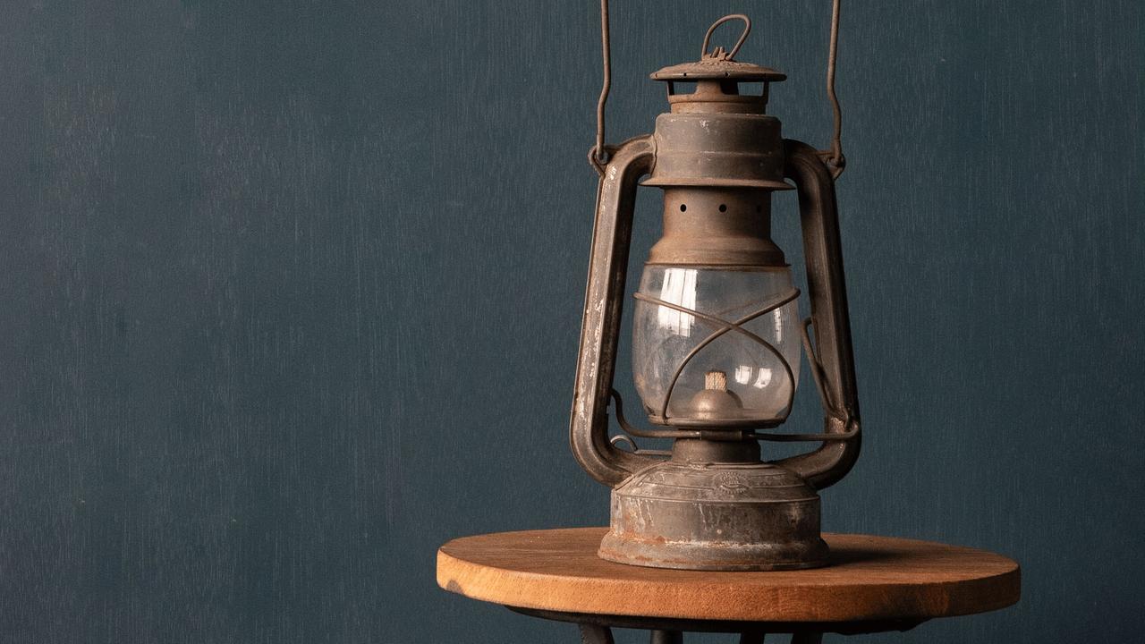 Eine alte Gaslampe steht auf einem runden kleinen Holztisch.