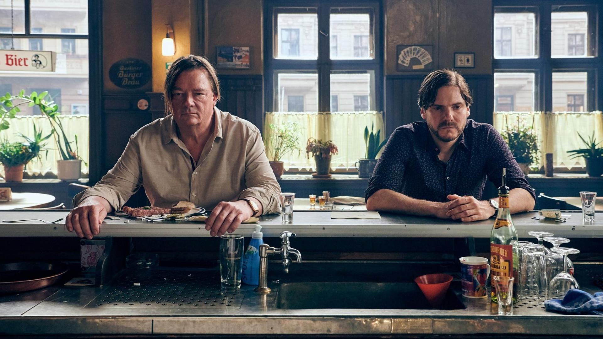 Filmszene aus Daniel Brühls Regie-Debüt "Nebenan". Zwei Männer sitzen an der Theke in einer Bar.