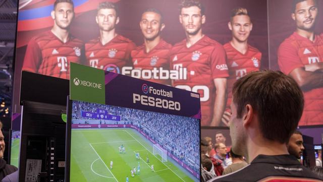 Spieler spielen das Spiel PES 2020 (Pro Evolution Soccer) vor Portraits einiger Spieler des FC Bayern München.