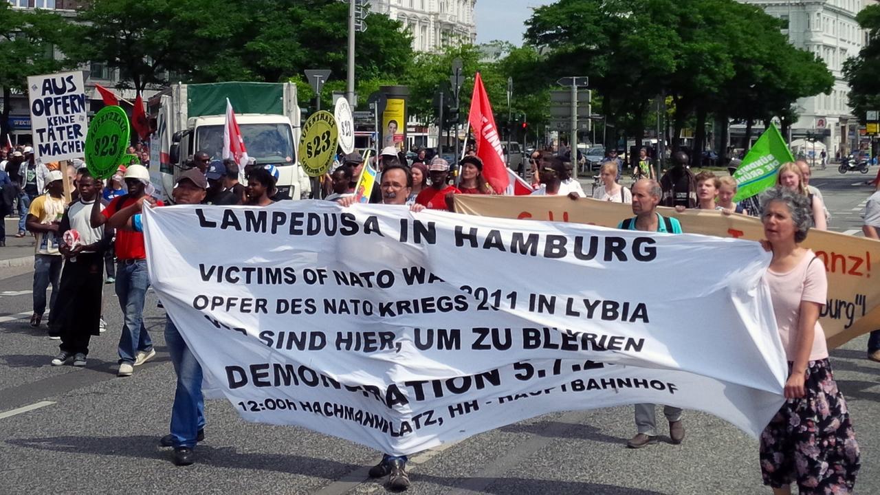 Demonstranten halten ein Plakat mit der Aufschrift "Lampedusa in Hamburg" hoch, aufgenommen 2014