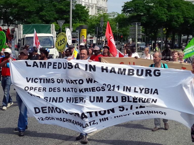 Demonstranten halten ein Plakat mit der Aufschrift "Lampedusa in Hamburg" hoch, aufgenommen 2014