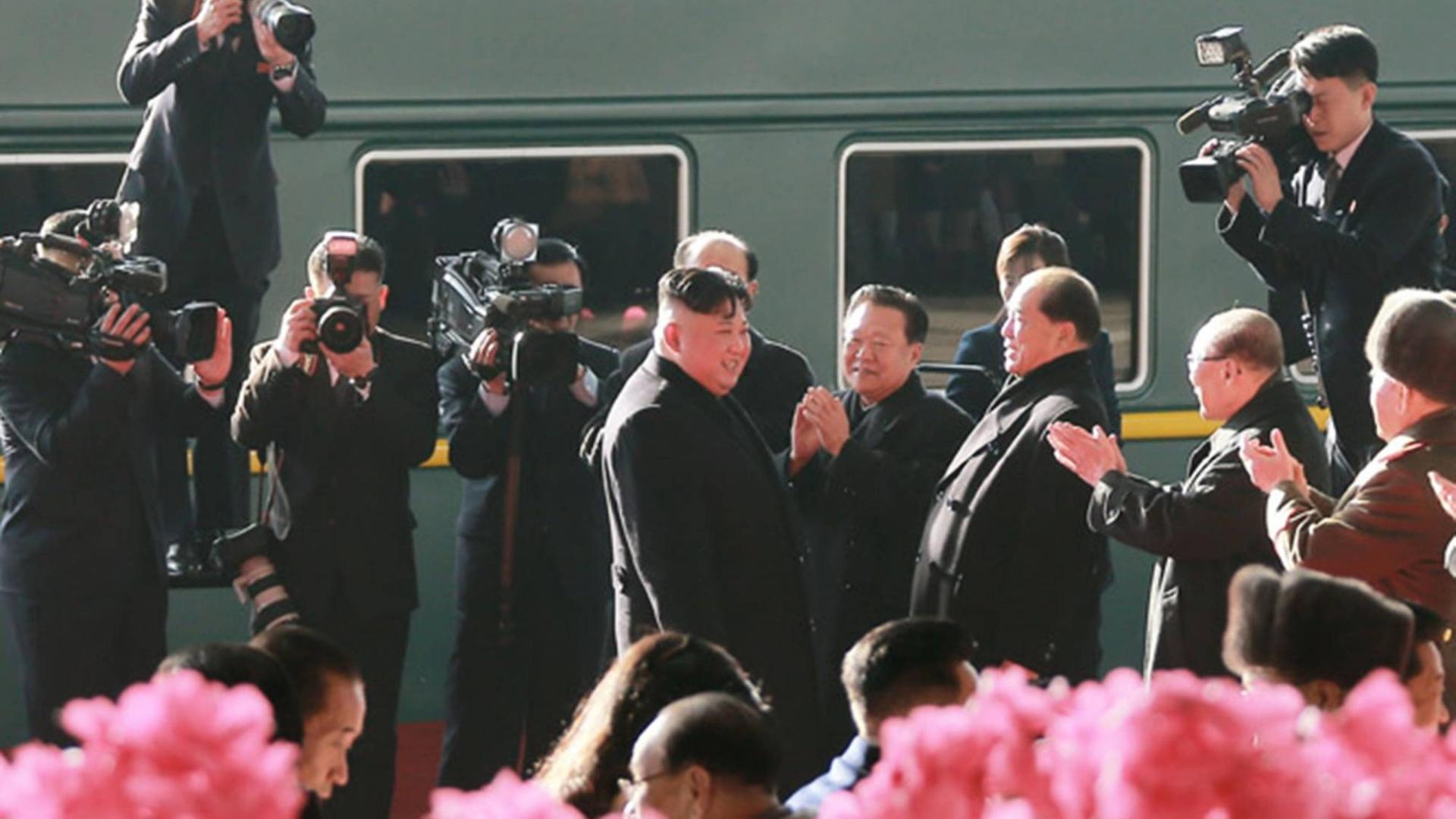 Kim Jung Un ist umringt von Kamerateams vor einem Zug zu sehen.