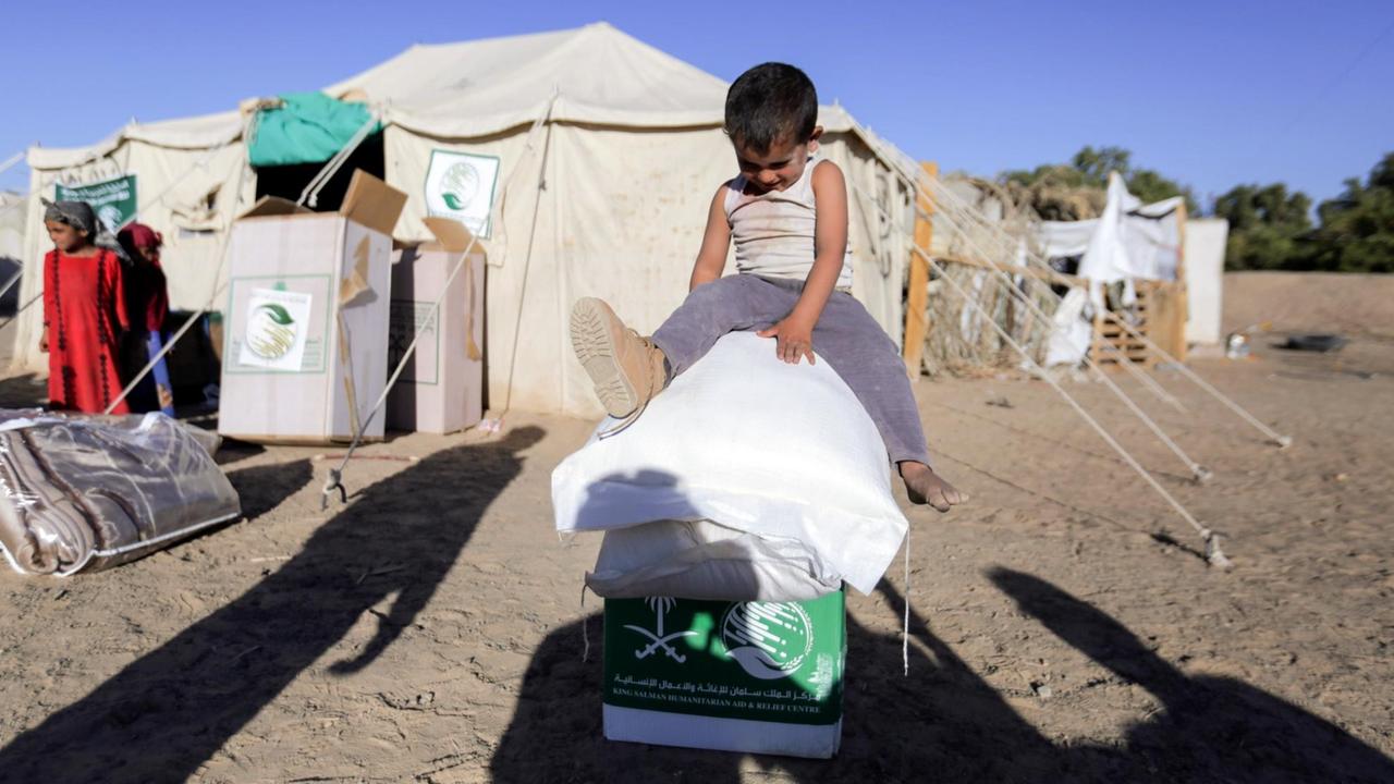 Ein vertriebenes jemenitisches Kind sitzt am 26. Januar 2018 auf Boxen und Säcken von Nahrungsmittel in einem Lagerder nordöstlichen Provinz Marib. Ein vertriebenes jemenitisches Kind sitzt am 26. Januar 2018 auf Boxen und Säcken von Nahrungsmittel in einem Lagerder nordöstlichen Provinz Marib.