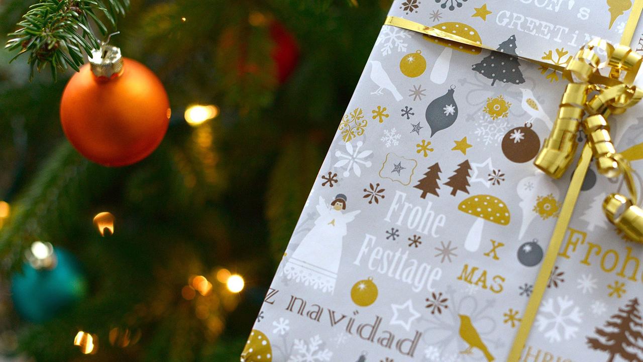 Ein eingepacktes Geschenk vor einem Christbaum. Ein eingepacktes Geschenk vor einem Christbaum.