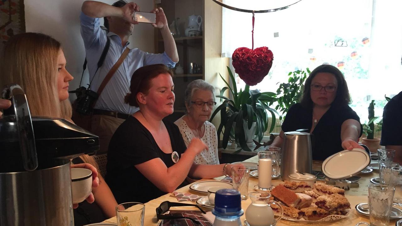 Andrea Nahles, SPD-Vorsitzende, sitzt mit Mietern in Hessen am Tisch bei Kaffee und Kuchen.