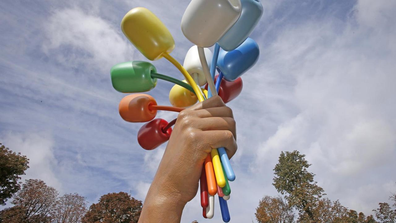 Jeff Koons Skulptur "Bouquet of Tulips": Eine riesige ausgestreckte Hand, die mehrere Tulpen überreicht. Jeff Koons Skulptur "Bouquet of Tulips": Eine riesige ausgestreckte Hand, die mehrere Tulpen überreicht.