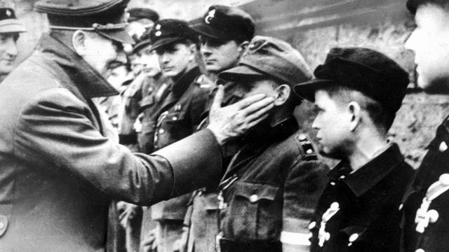 Eine der letzten Aufnahmen von Adolf Hitler vom 20.03.1945 zeigt ihn bei der Auszeichnung von Mitgliedern der Berliner Hitler-Jugend, die zum Ende des Zweiten Weltkrieges in Volkssturmeinheiten zusammengefaßt wurden.