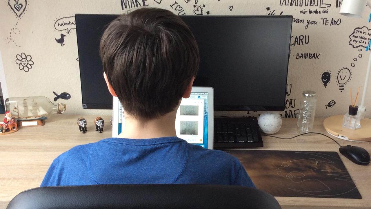 Ein Junge an seinem Schreibtisch vor seinem Computer - von hinten aufgenommen. Ein Junge an seinem Schreibtisch vor seinem Computer - von hinten aufgenommen.