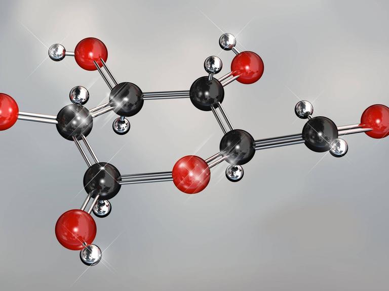 Ein Modell eines Glucose-Moleküls: schwarze und rote Kugeln an einem silbernen Gestänge