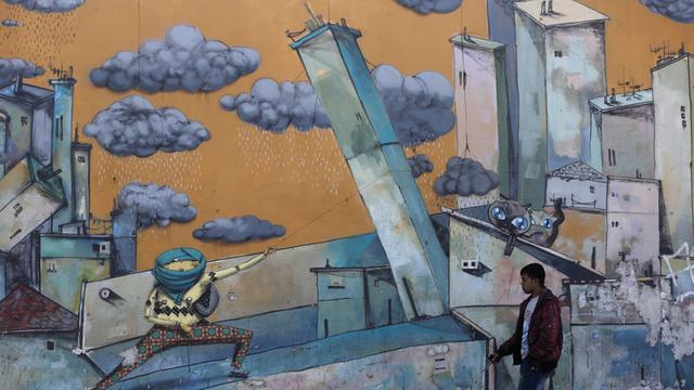 Mann vor einer Graffiti-Wand in Athen