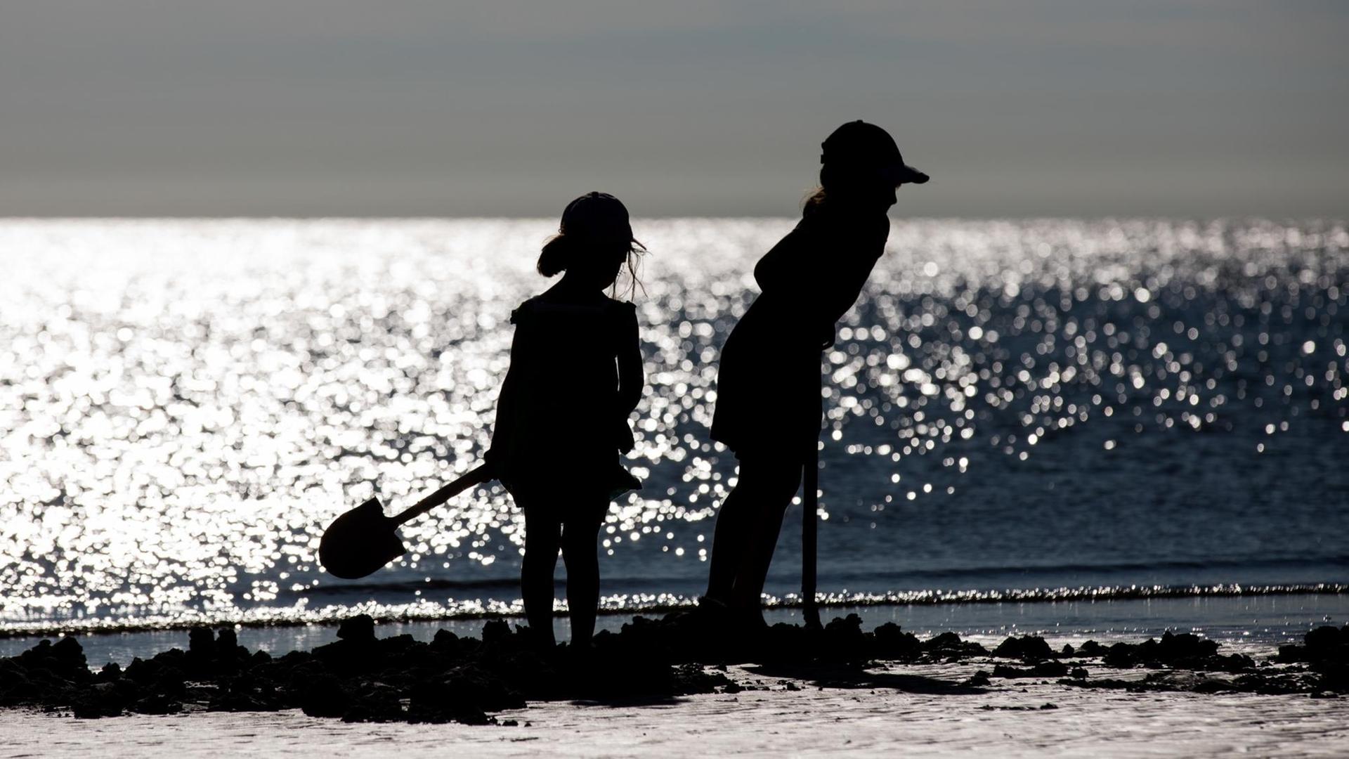 Zwei Kinder spielen an einem Strand mit Schaufeln. Zwei Kinder spielen an einem Strand mit Schaufeln.