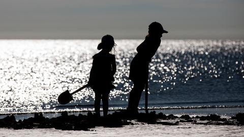 Zwei Kinder spielen an einem Strand mit Schaufeln.