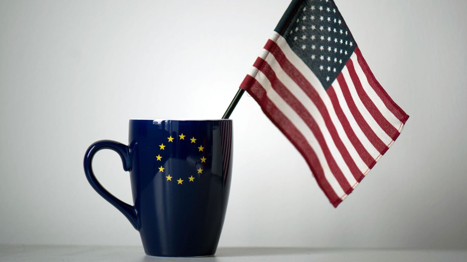 In einer Tasse mit einem EU-Symbol steckt eine US-Fahne, aufgenommen in einem Büro in Dresden. In einer Tasse mit einem EU-Symbol steckt eine US-Fahne, aufgenommen in einem Büro in Dresden.